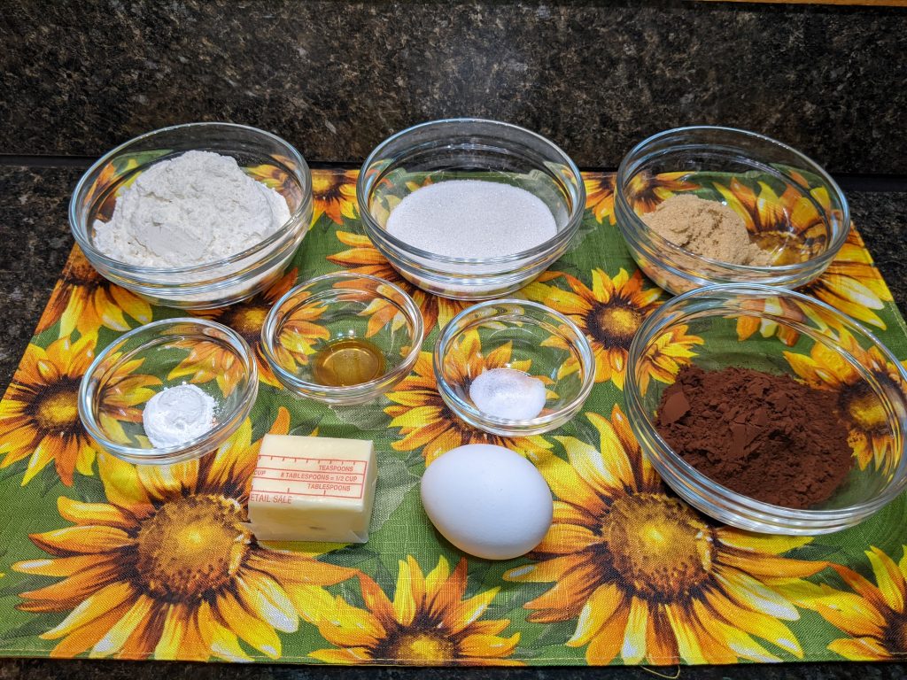 Cookie ingredients in glass bowls on a sunflower placemat.