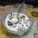 A small glass bowl with edible cookie dough and a layer of cheesecake cream on top.