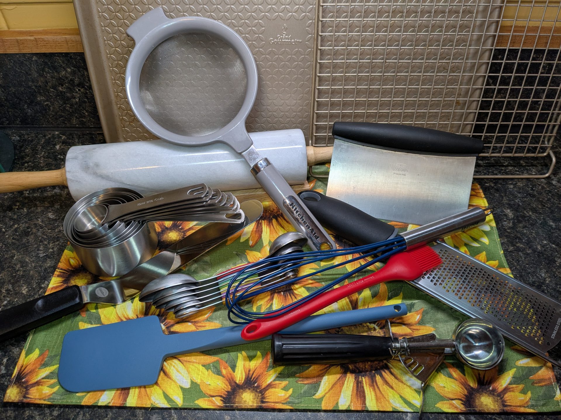 A pile of assorted baking tools and supplies, ranging from cookie sheets to measuring spoons.