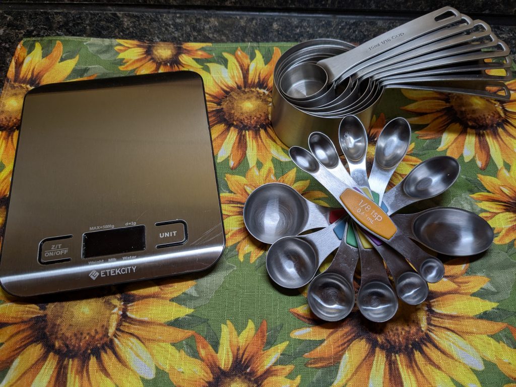 A photo of a kitchen scale, a set of measuring cups, and a set of measuring spoons.