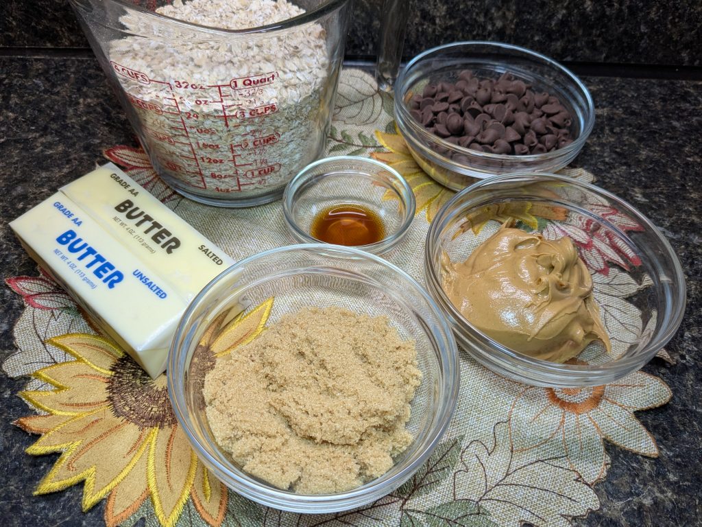 A picture of the ingredients for no-bake bars; oats, chocolate chips, butter, vanilla extract, peanut butter, and brown sugar.